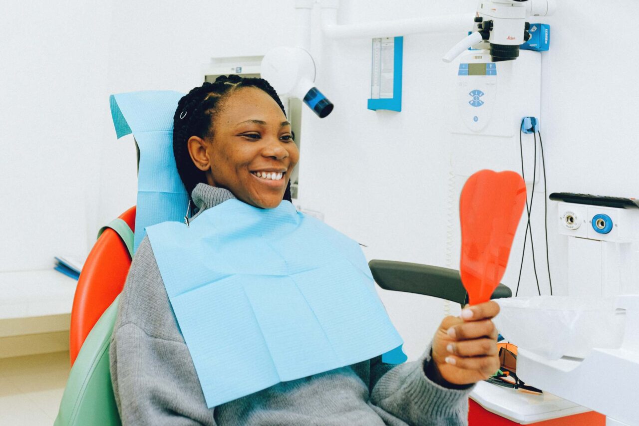 Woman seeing her smile with a mirror in a dental clinic